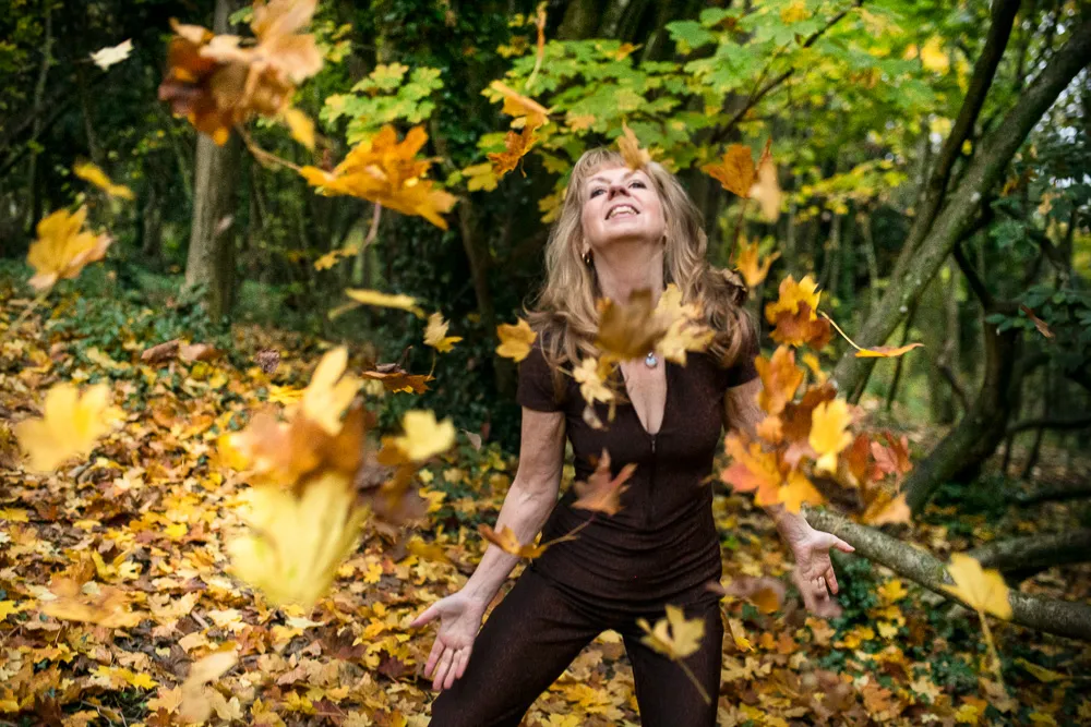 Jilly in the woods throwing dead leaves in the air